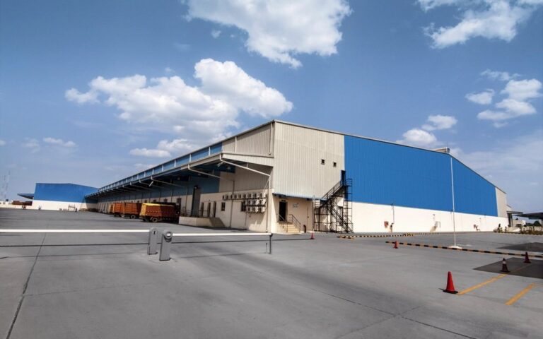 Industrial manufacturing building with a blue and white facade under a clear sky